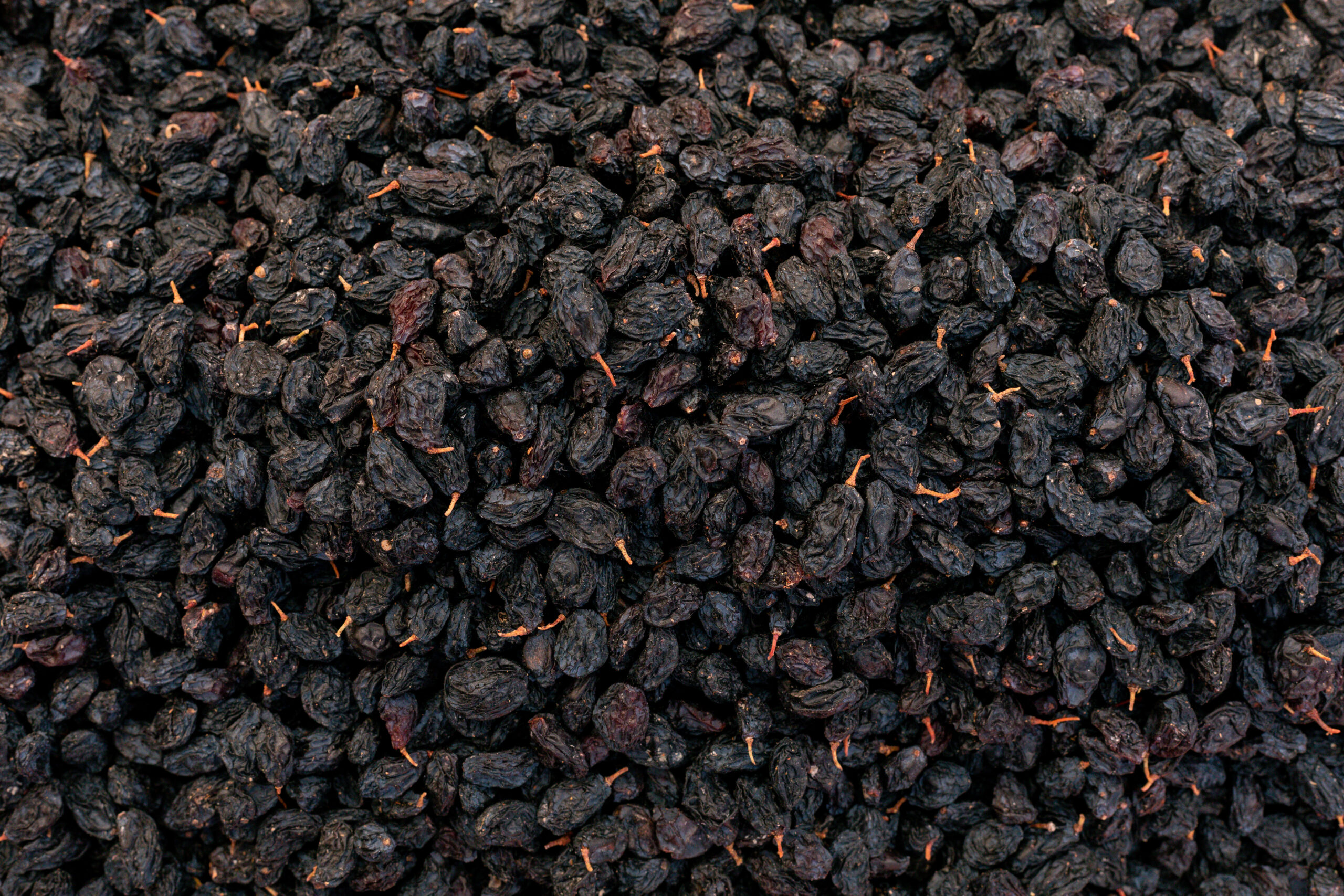black sweet raisins dried sweet grapes background